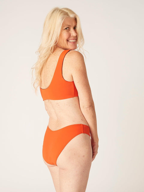 Modibodi Recycled Swimwear Brazilian Brief Sunset Orange|ModelName: Jane 10/S